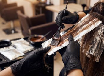 Proceso de tinte de cabello en salón con papel aluminio y guantes profesionales