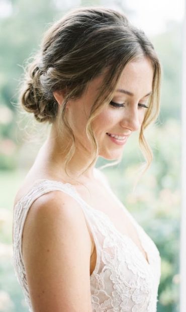 Mujer luciendo un elegante peinado recogido y vestido de encaje, ideal para bodas.
